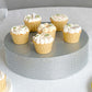 Silver rhinestone cake stand with cupcakes on a gray surface.