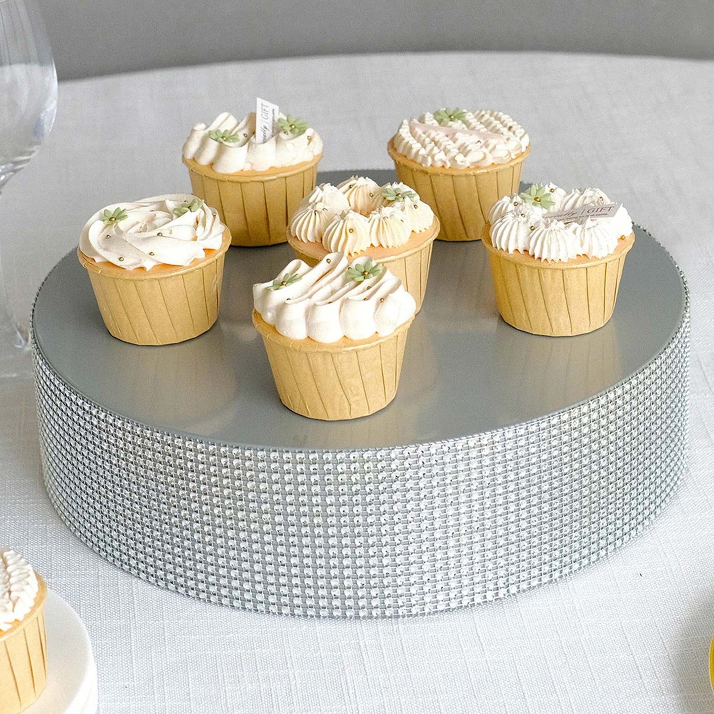 Silver rhinestone cake stand with cupcakes on a gray surface.