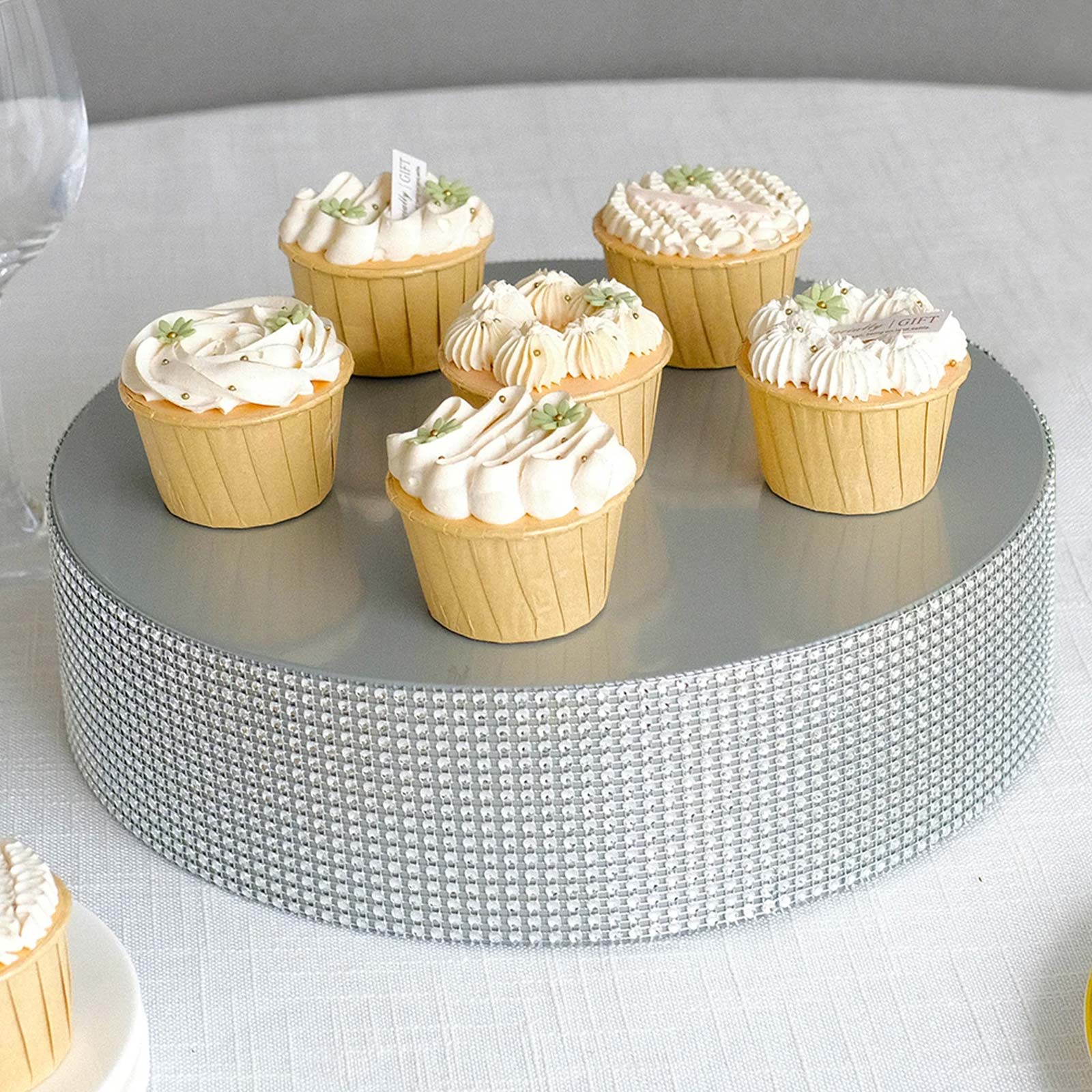 Silver rhinestone cake stand with cupcakes on a gray surface.