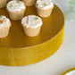 Gold round metal pedestal cake stand with cupcakes on display.