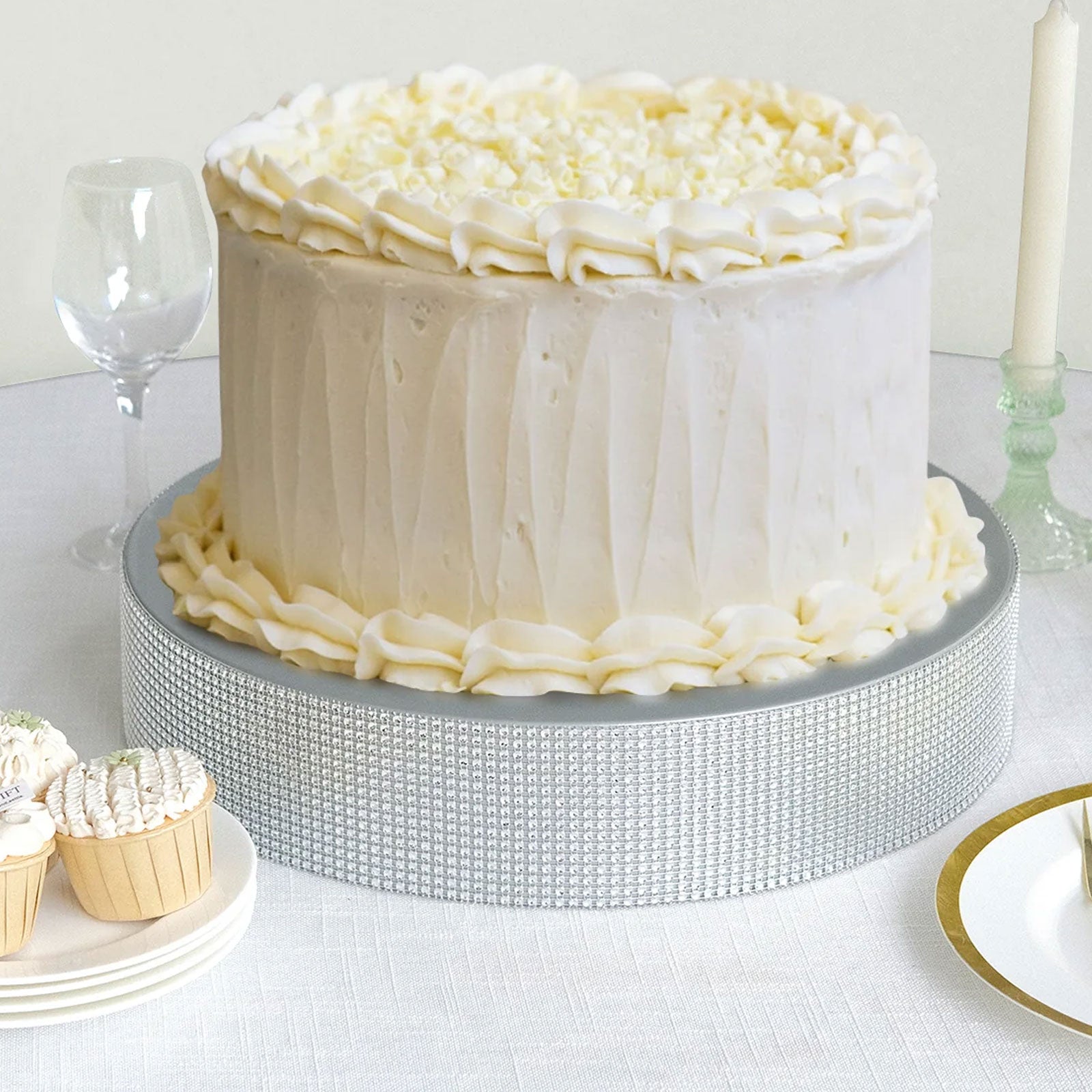 Silver round metal pedestal cake stand with rhinestones, displaying a cake and cupcakes.