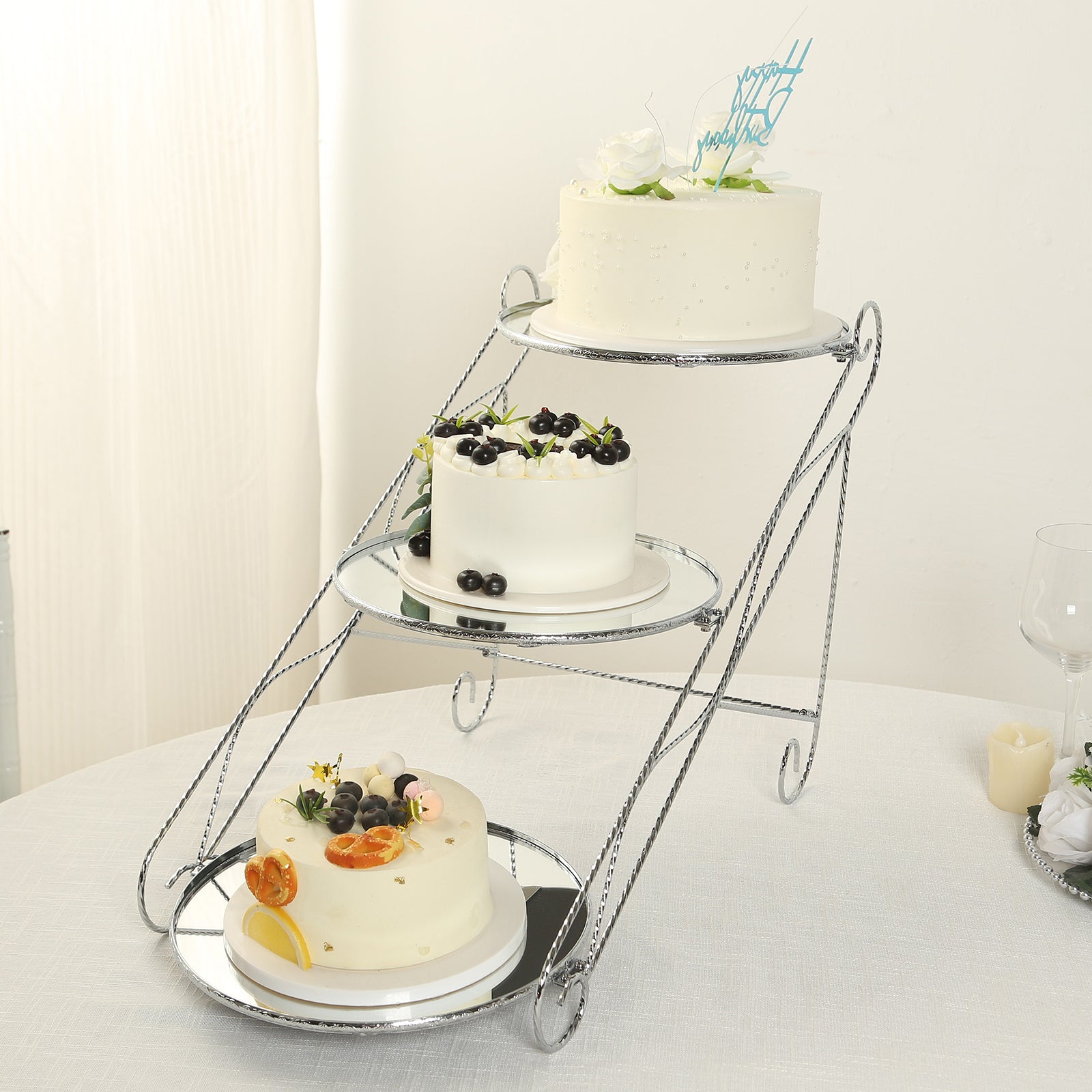Silver 3-tier cupcake stand with mirror trays displaying decorated cakes.
