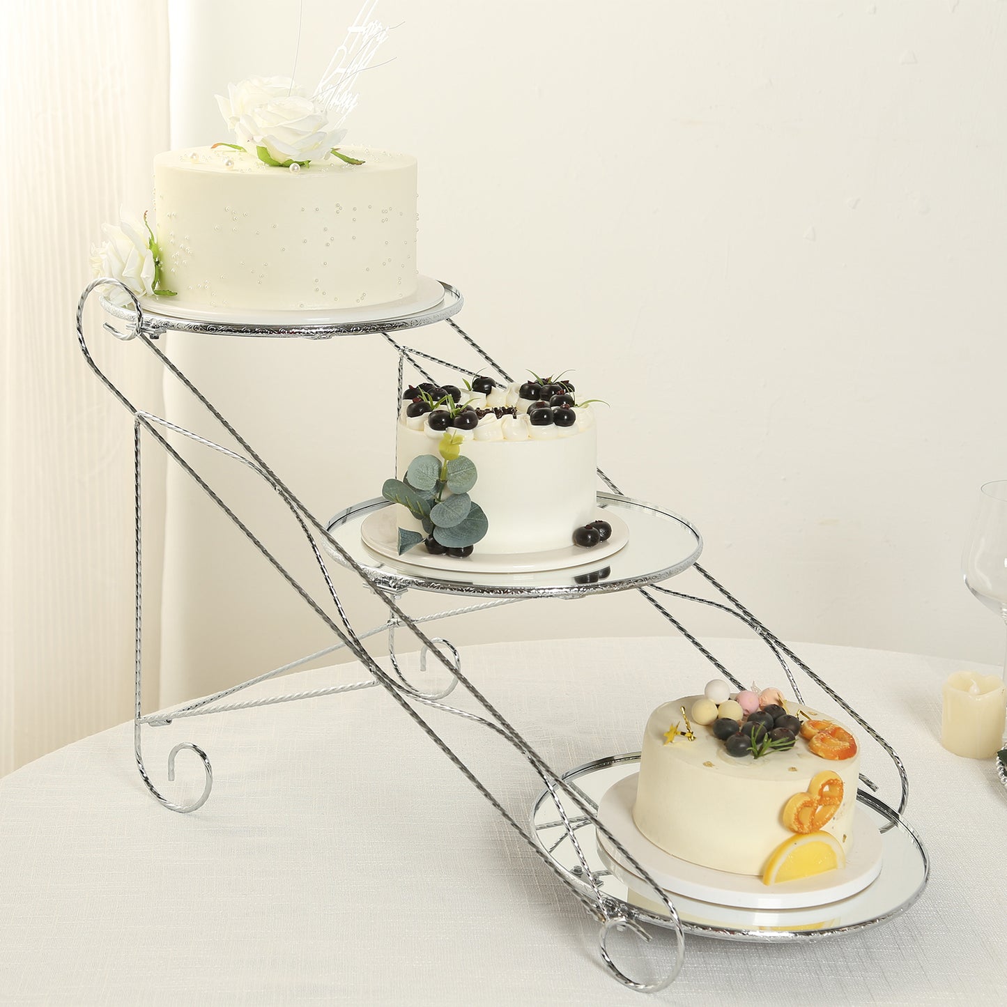 Silver cascading metal cupcake stand with round mirror trays displaying desserts.