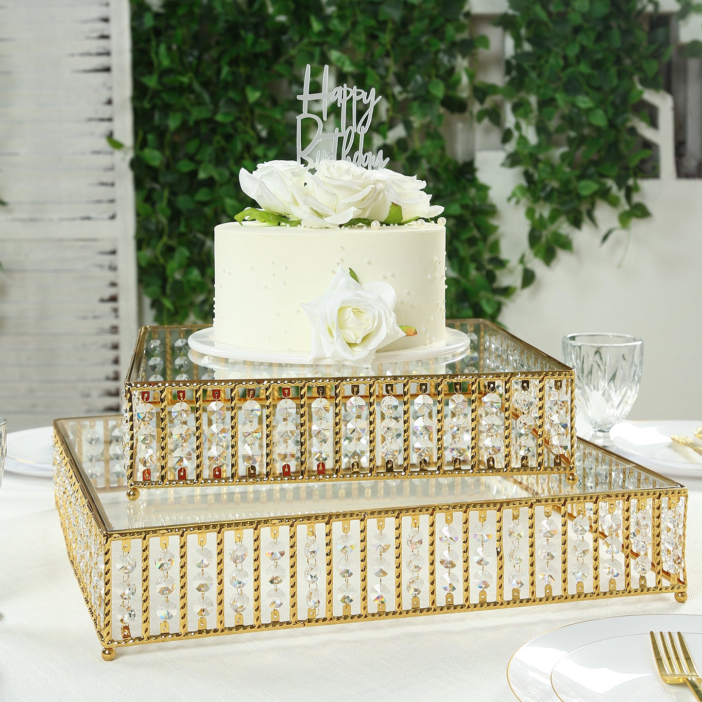 Gold cake stand with hanging crystal beads and glass top for dessert display.