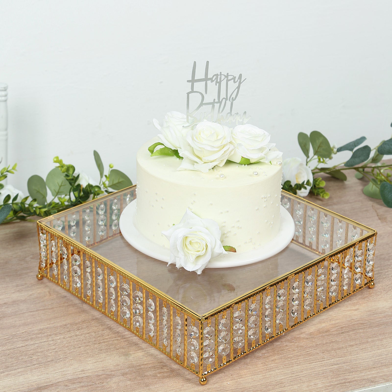 Gold cake stand with hanging crystal beads and glass top, perfect for desserts.