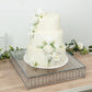 Silver cake stand with hanging crystal beads, displaying a white floral cake.