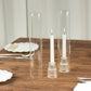 Clear glass candle shades with white candles on a wooden table.