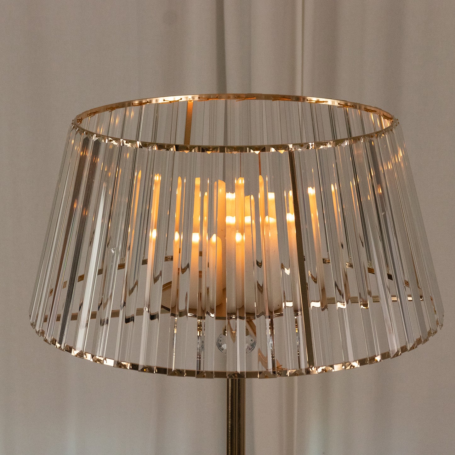 Gold crystal pendant candle holder with warm glowing candles.