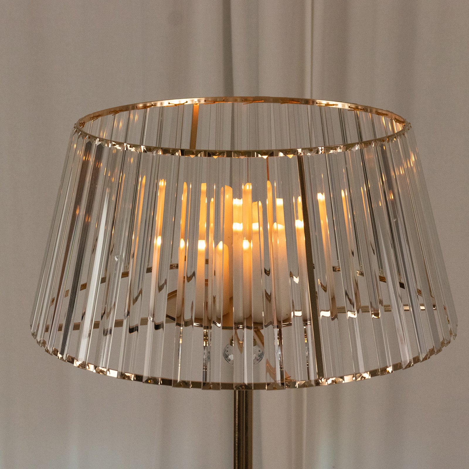 Gold crystal pendant candle holder with warm glowing candles.
