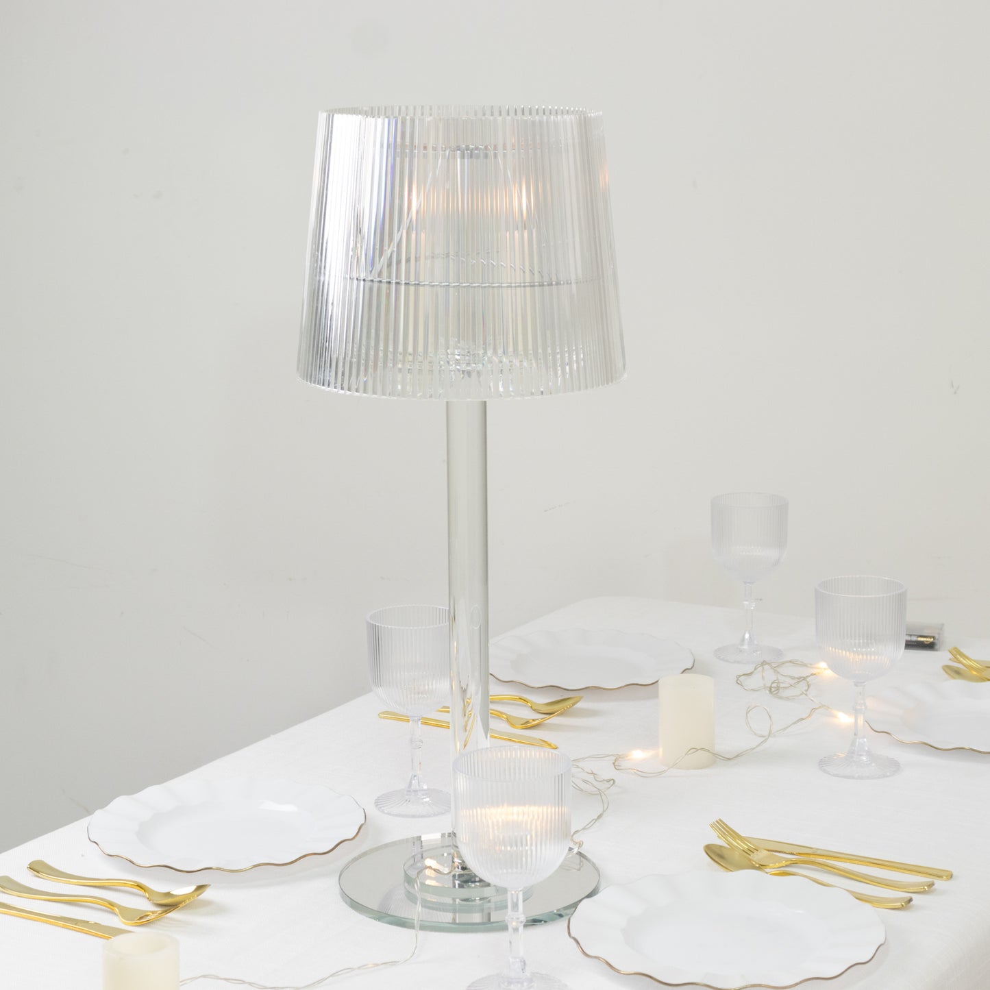 Clear acrylic candle lamp with ribbed shade on a table setting.