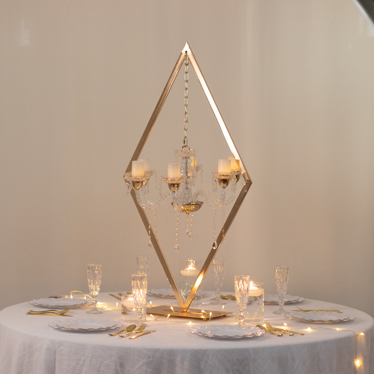 Gold acrylic candelabra centerpiece with candle holders on a table.