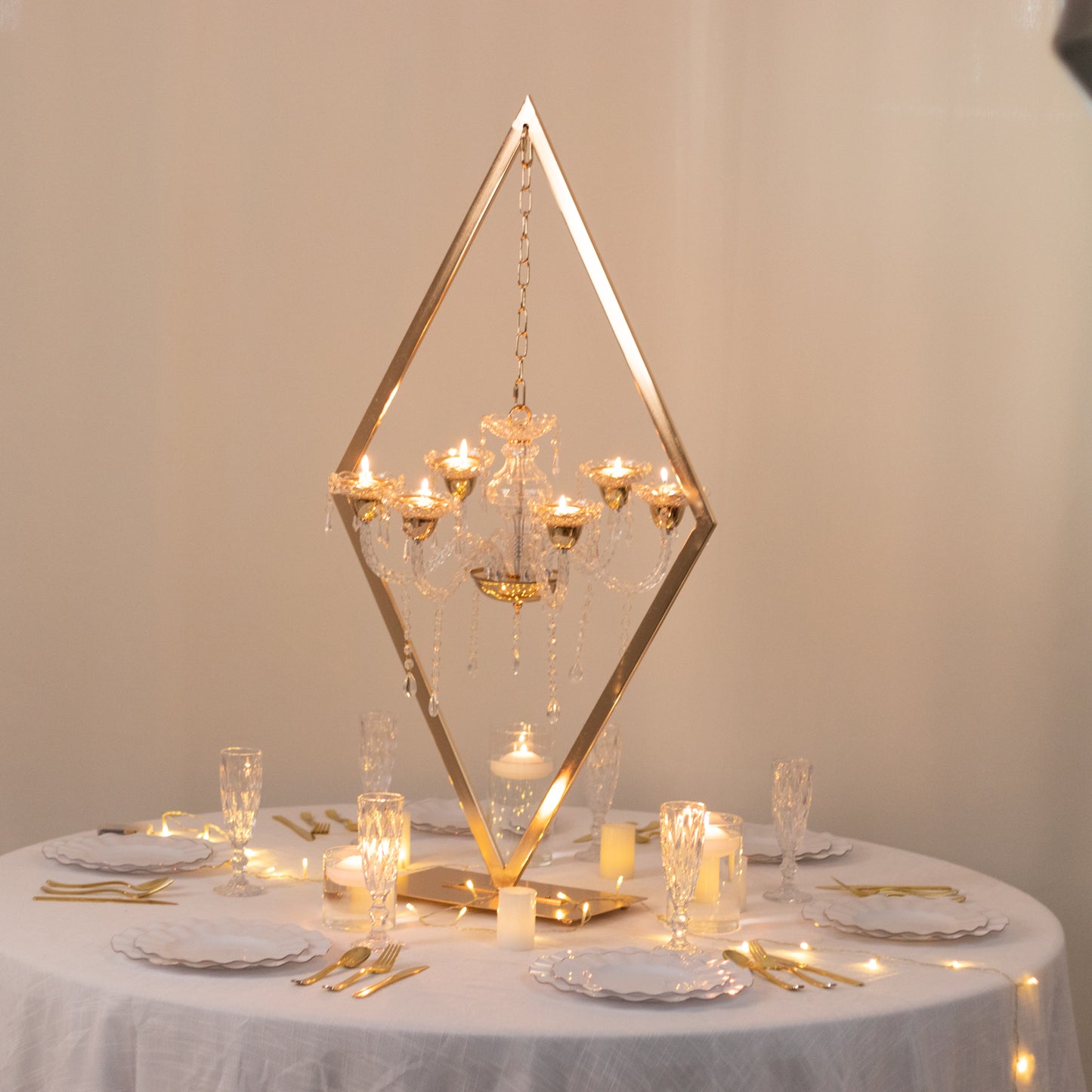 Gold 6-arm acrylic candelabra centerpiece on a table with candle holders.