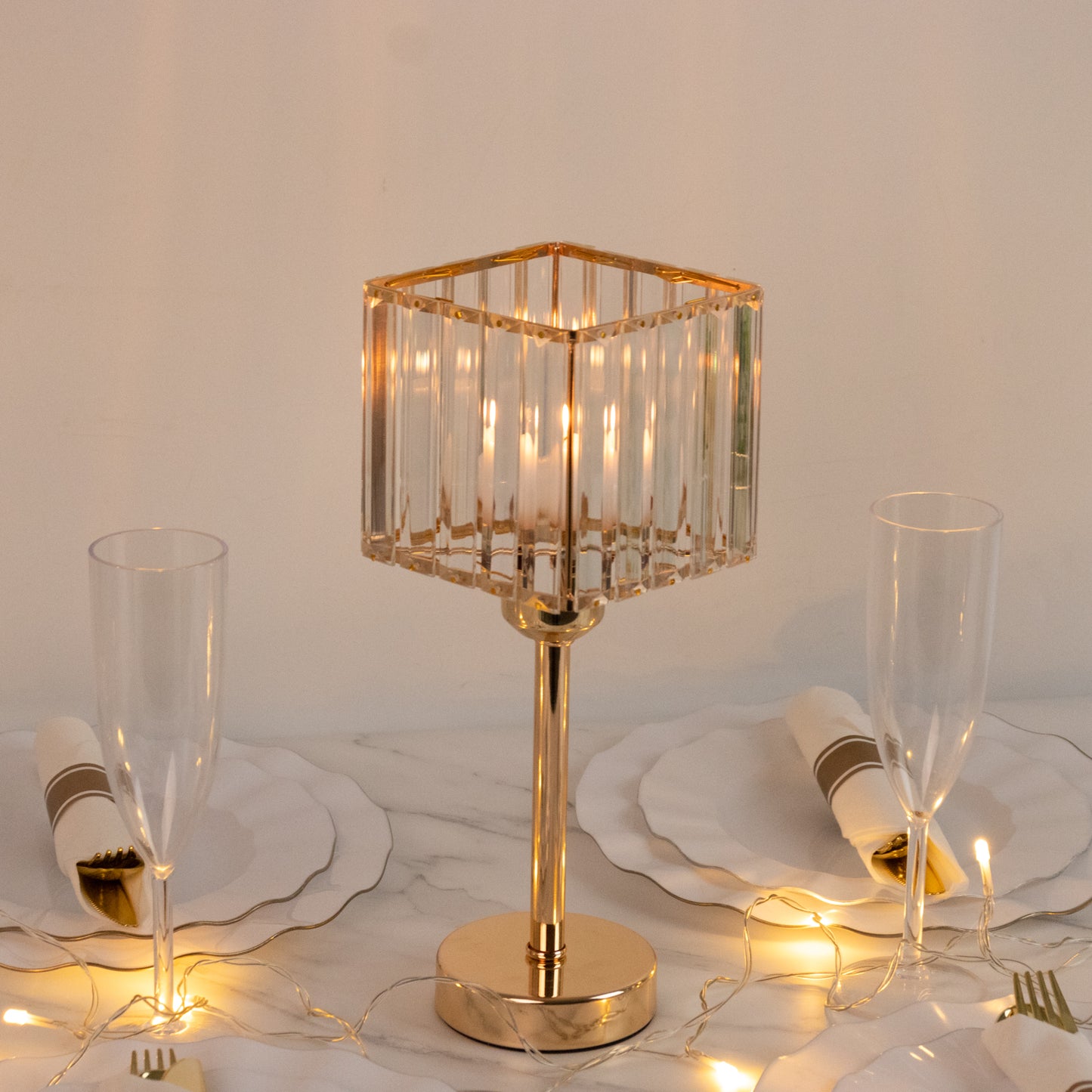 Gold crystal hurricane candle holder on a table with elegant decor.