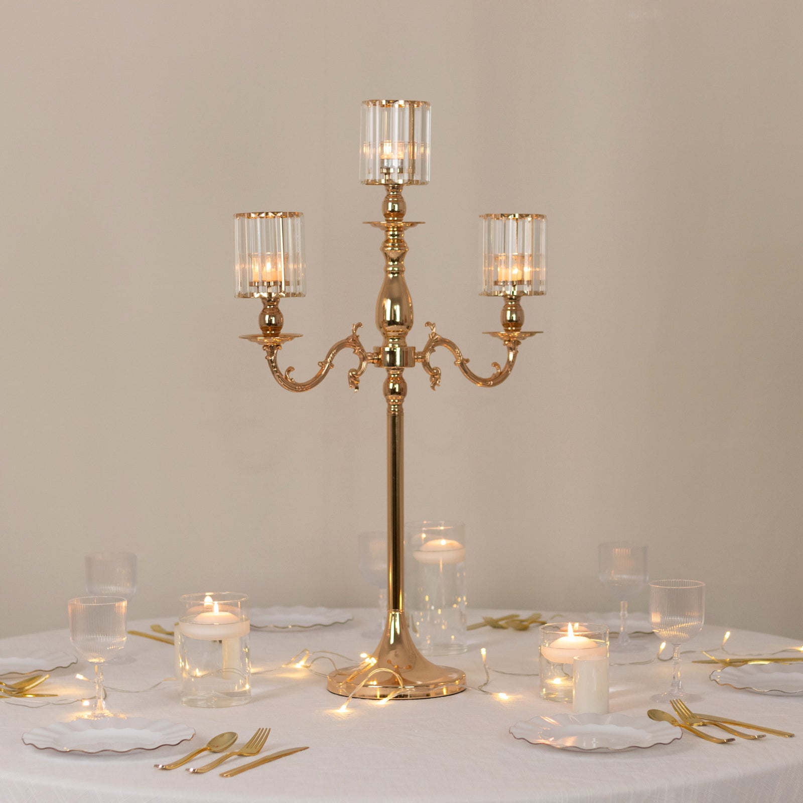 Gold metal 3-arm candelabra with crystal shades on a dining table.