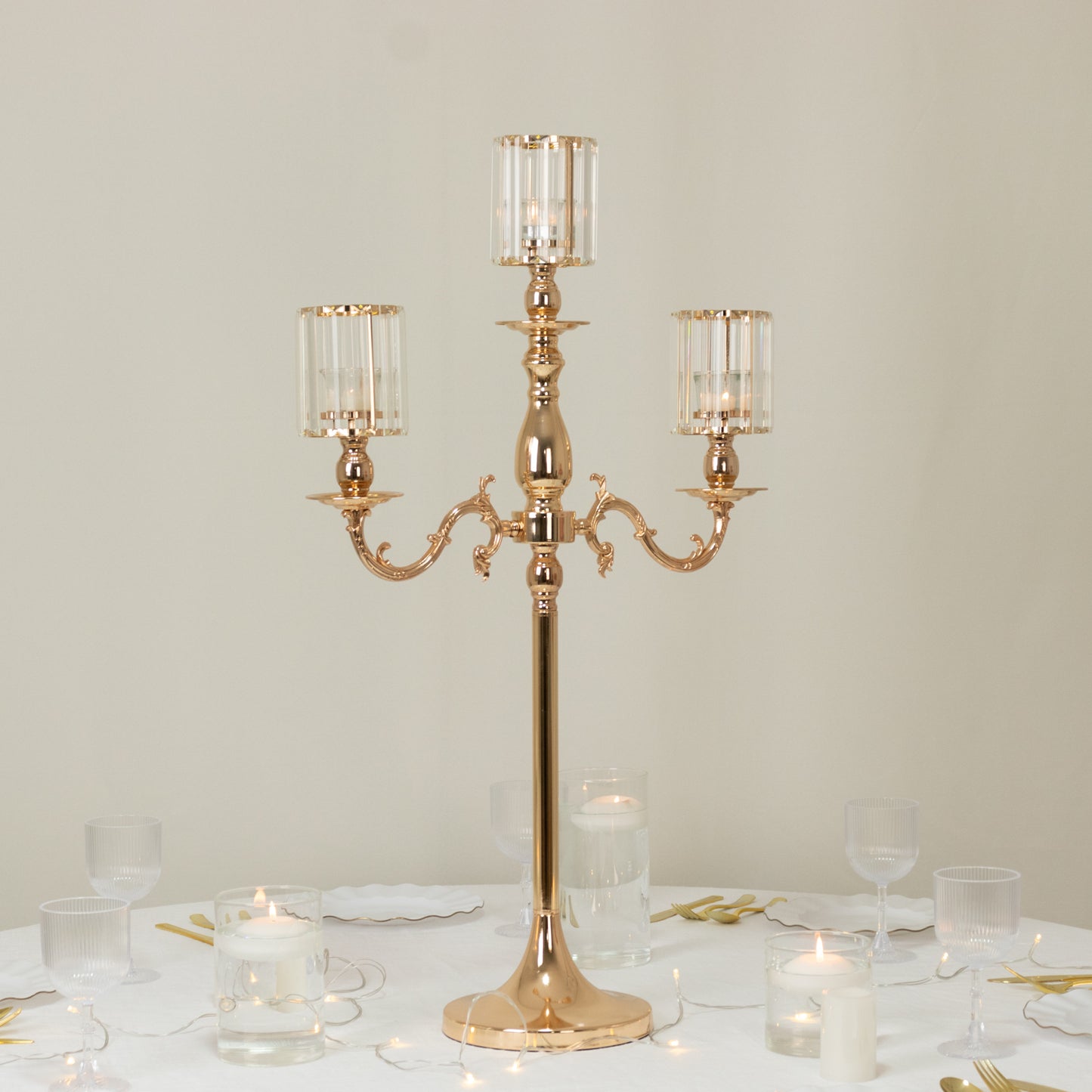 Gold metal 3-arm candelabra with crystal shades on a table setting.