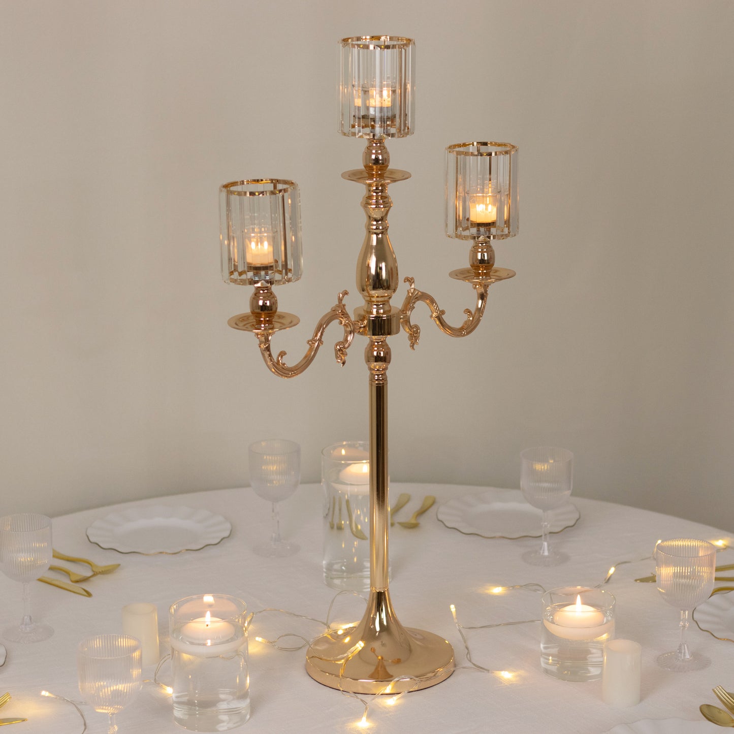 Gold 3-arm candelabra with crystal shades on a table setting.
