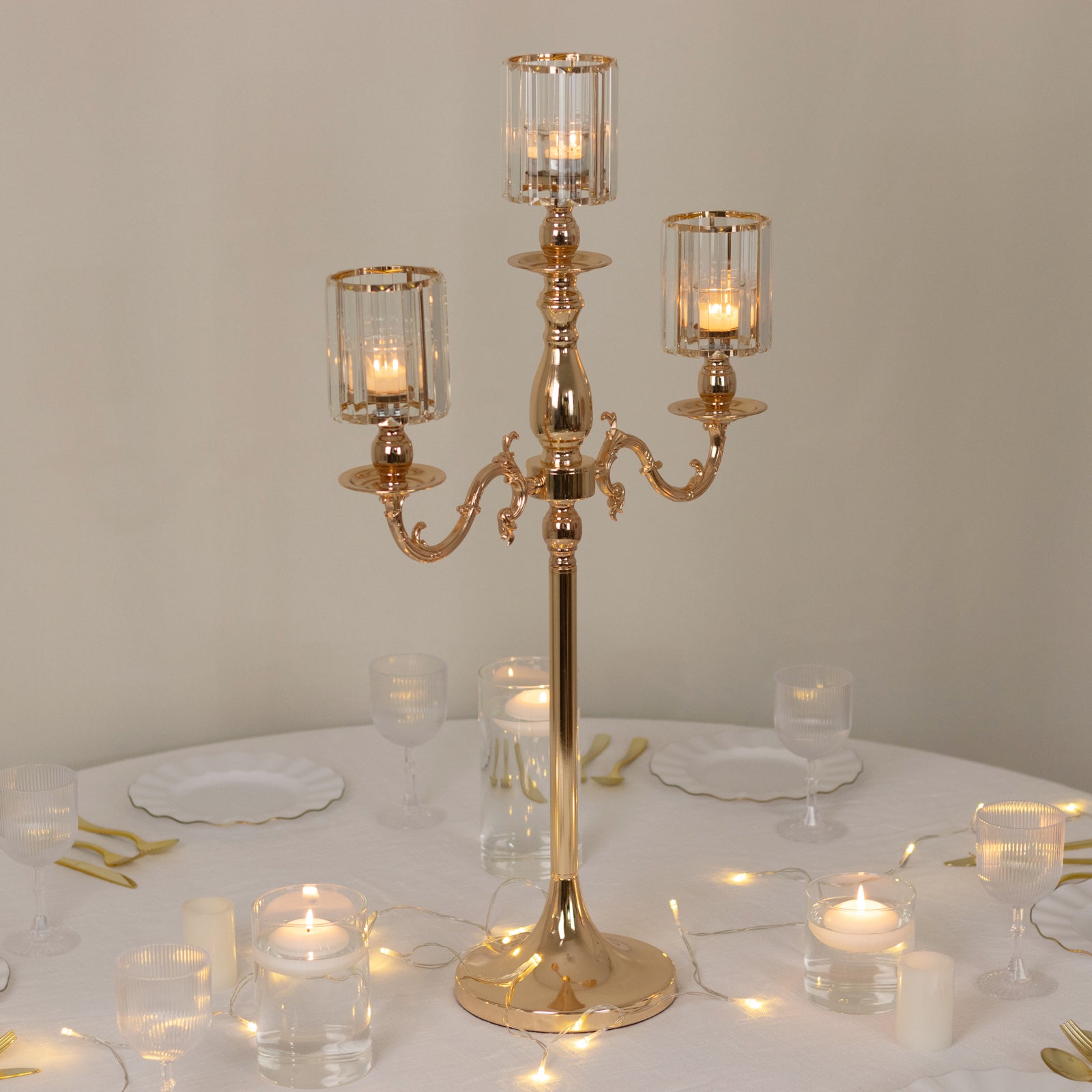 Gold 3-arm candelabra with crystal shades on a table setting.