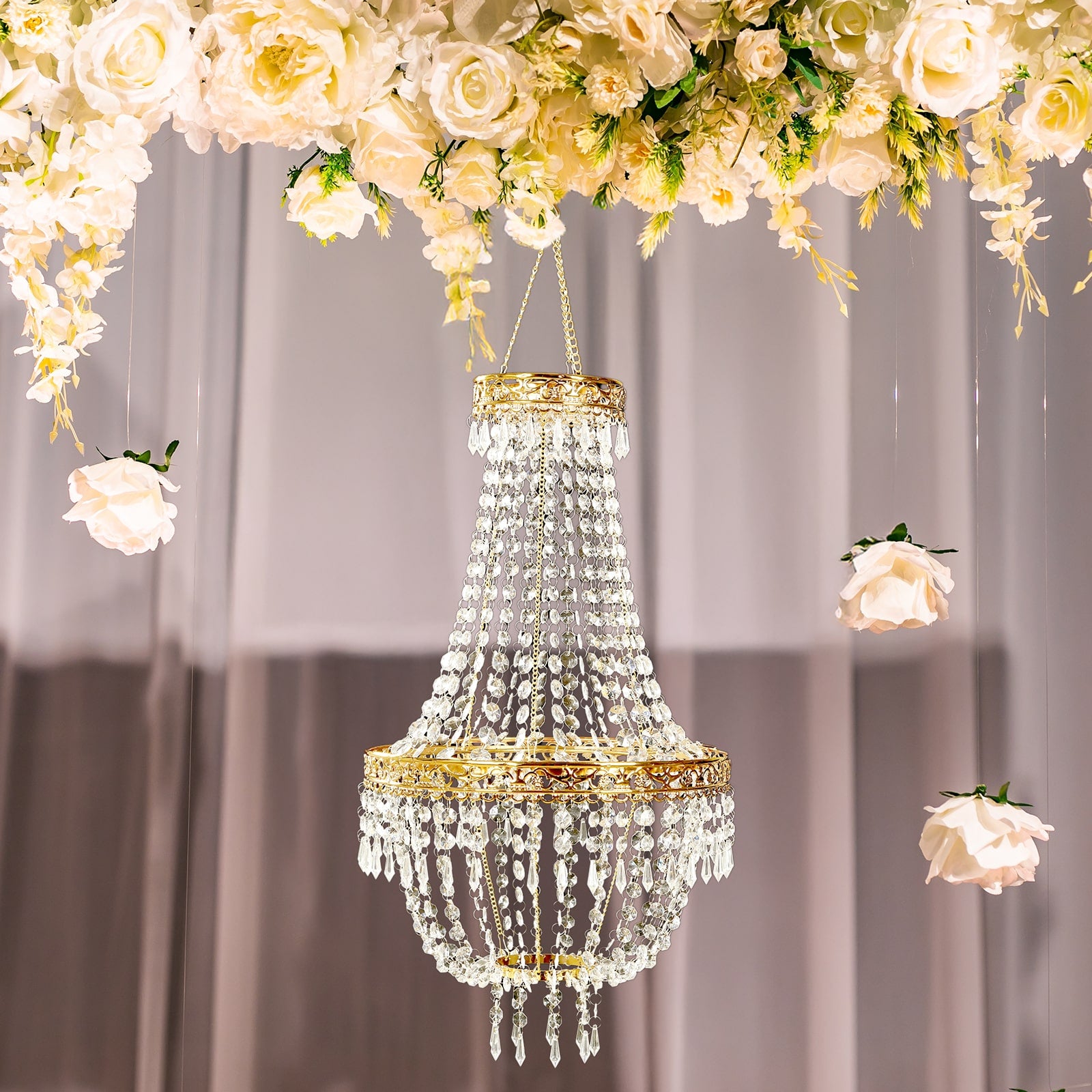 Gold beaded crystal chandelier with ornate metal frame and floral backdrop.