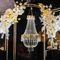 Gold beaded crystal chandelier with ornate frame and floral decor.