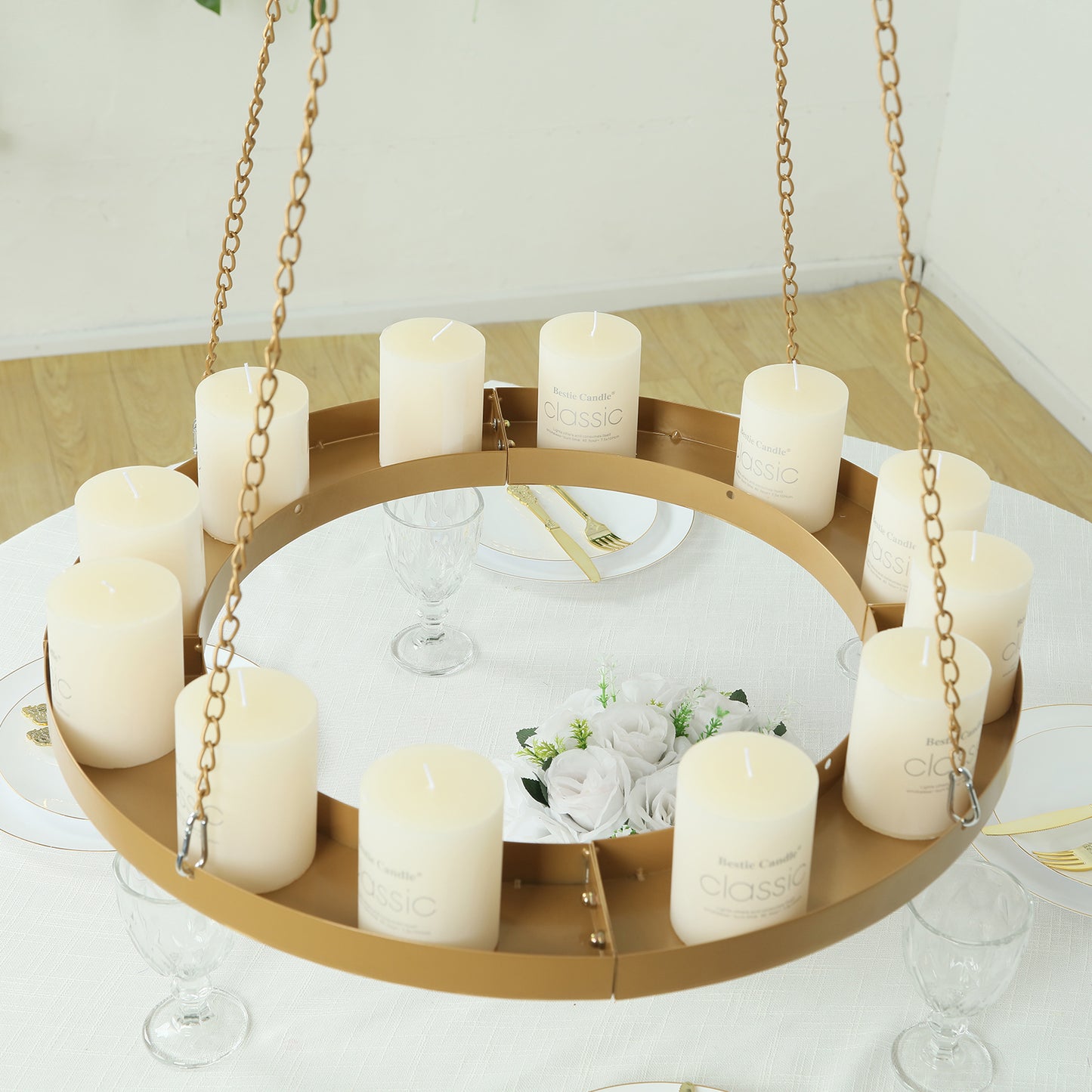 Gold hanging metal floral chandelier frame with candles and floral display.