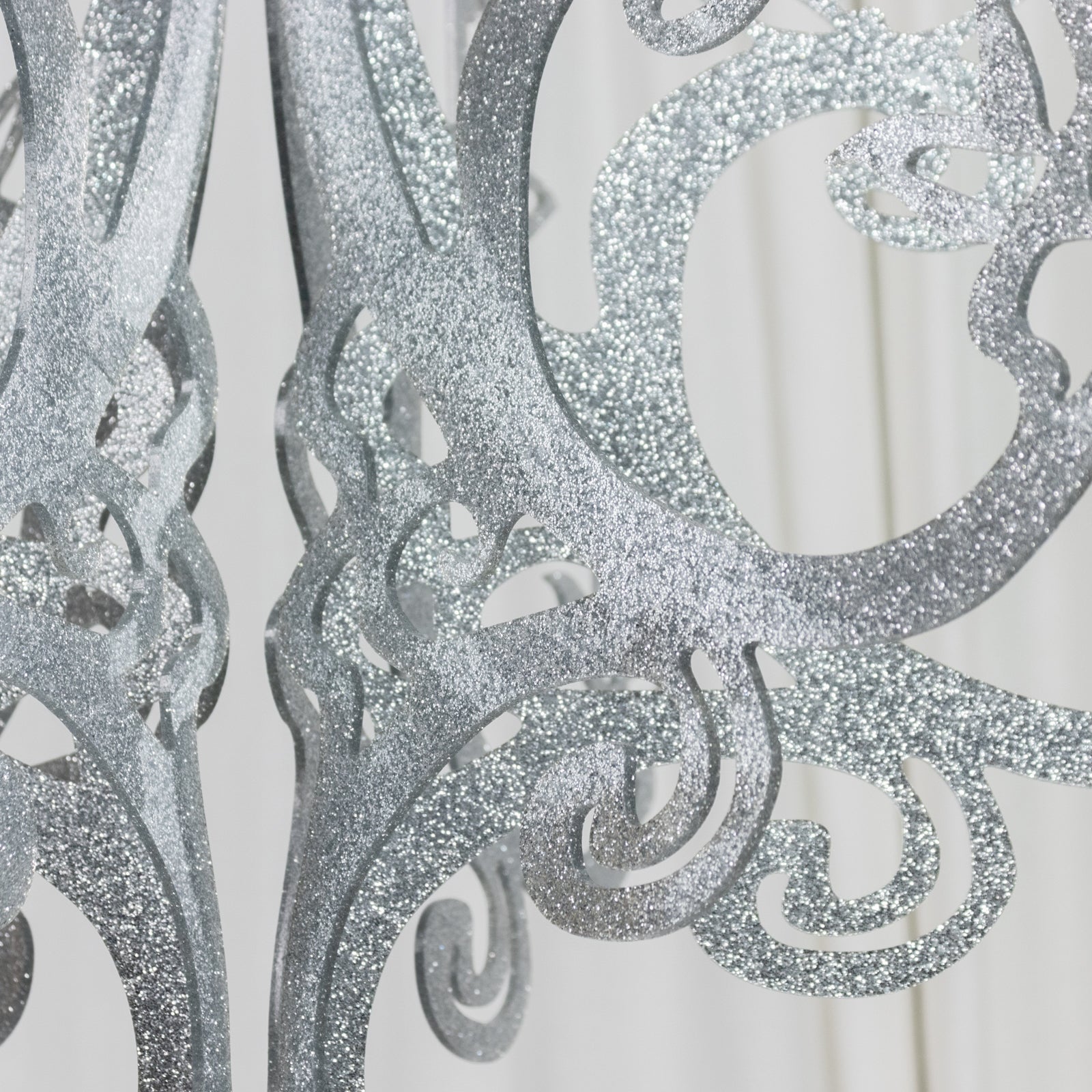 Silver glittered acrylic chandelier decor with 3D interlocking cutout design.