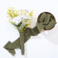 Dusty sage green chiffon ribbon roll with floral arrangement.