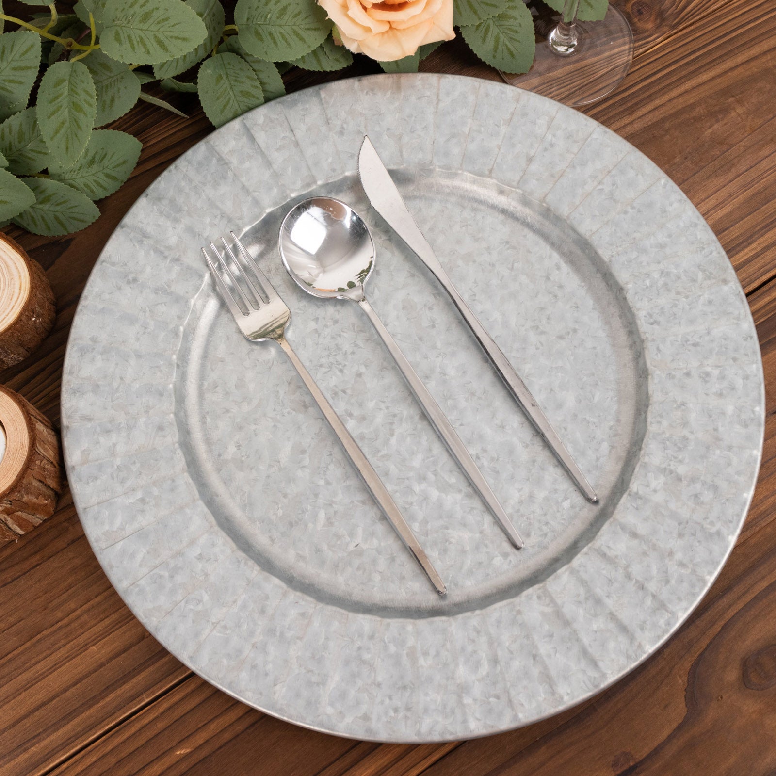 Silver galvanized metal charger plate with ruffled rim and silver utensils.
