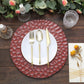 Burgundy hammered charger plate with gold flatware on a wooden table setting.