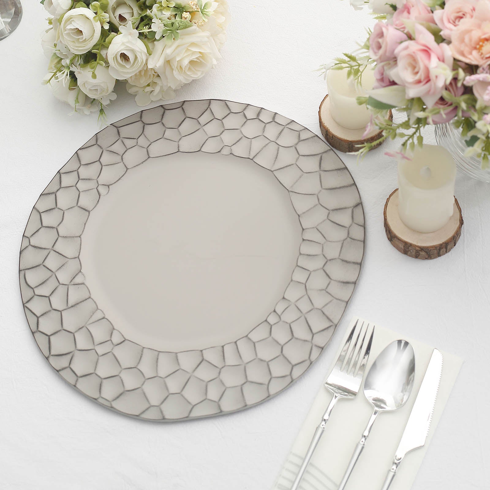 Matte gray hammered charger plate on a table setting with flowers and candles.