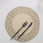 Matte finish taupe hammered charger plate with black utensils on a white tablecloth.