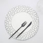 White plate with unique black geometric design, fork and knife set on table.