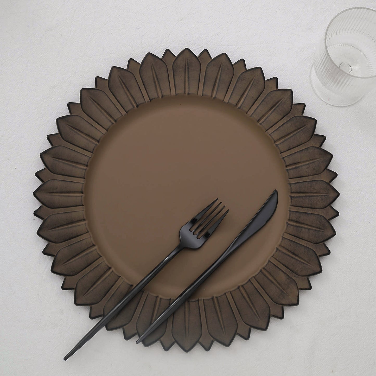 Matte natural sunflower disposable charger plate with black utensils.