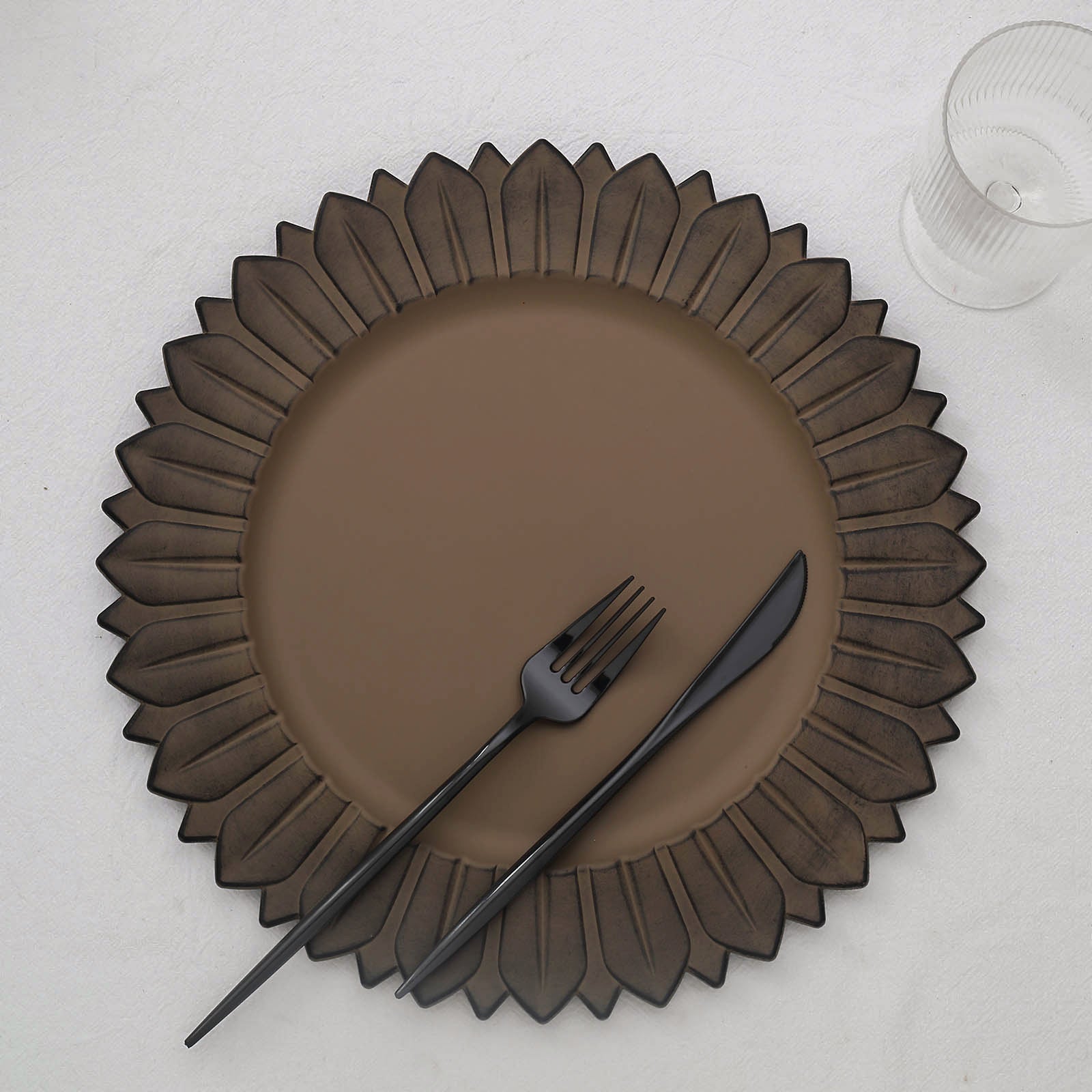 Matte natural sunflower disposable charger plate with black utensils.