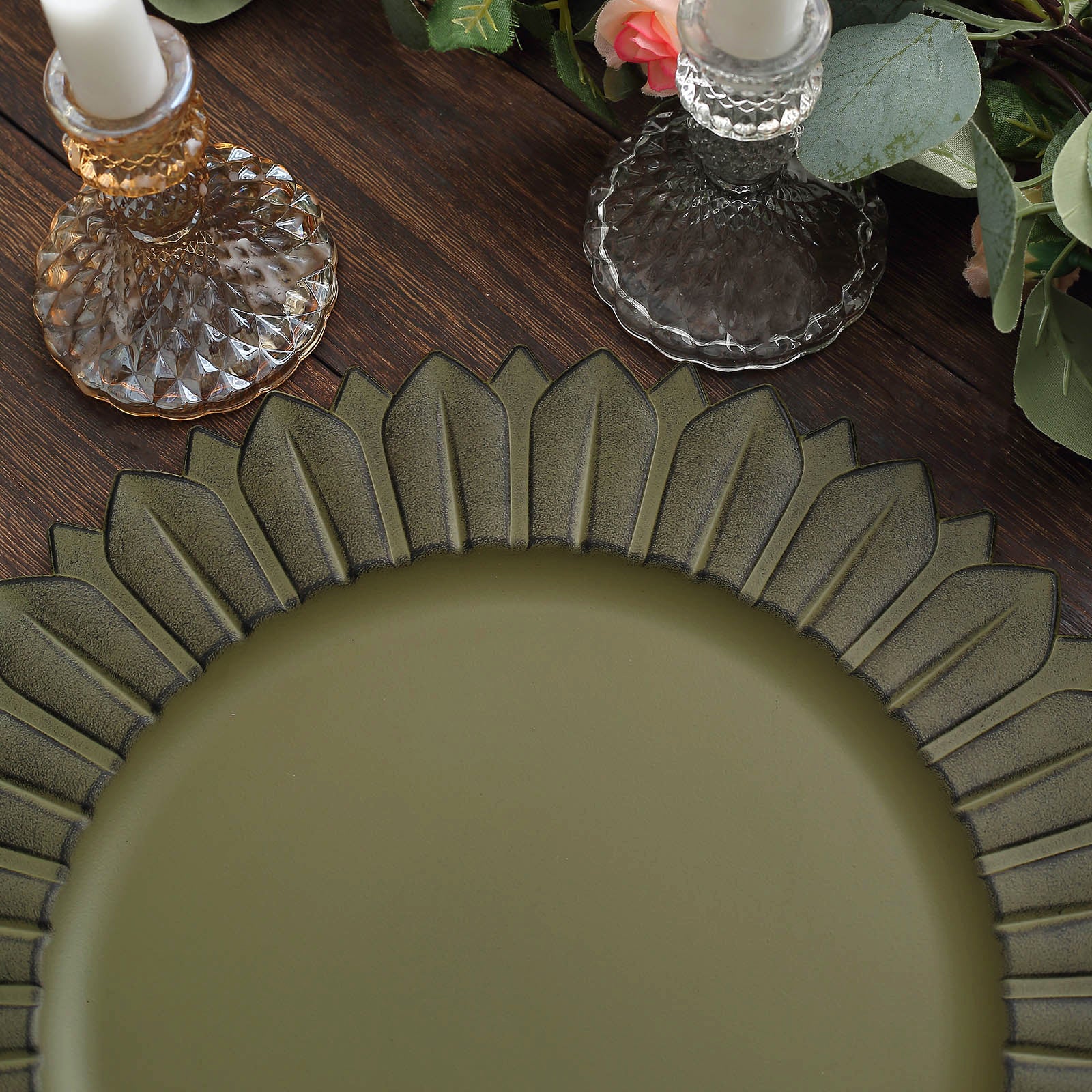 Matte olive green sunflower disposable charger plates on a wooden table.