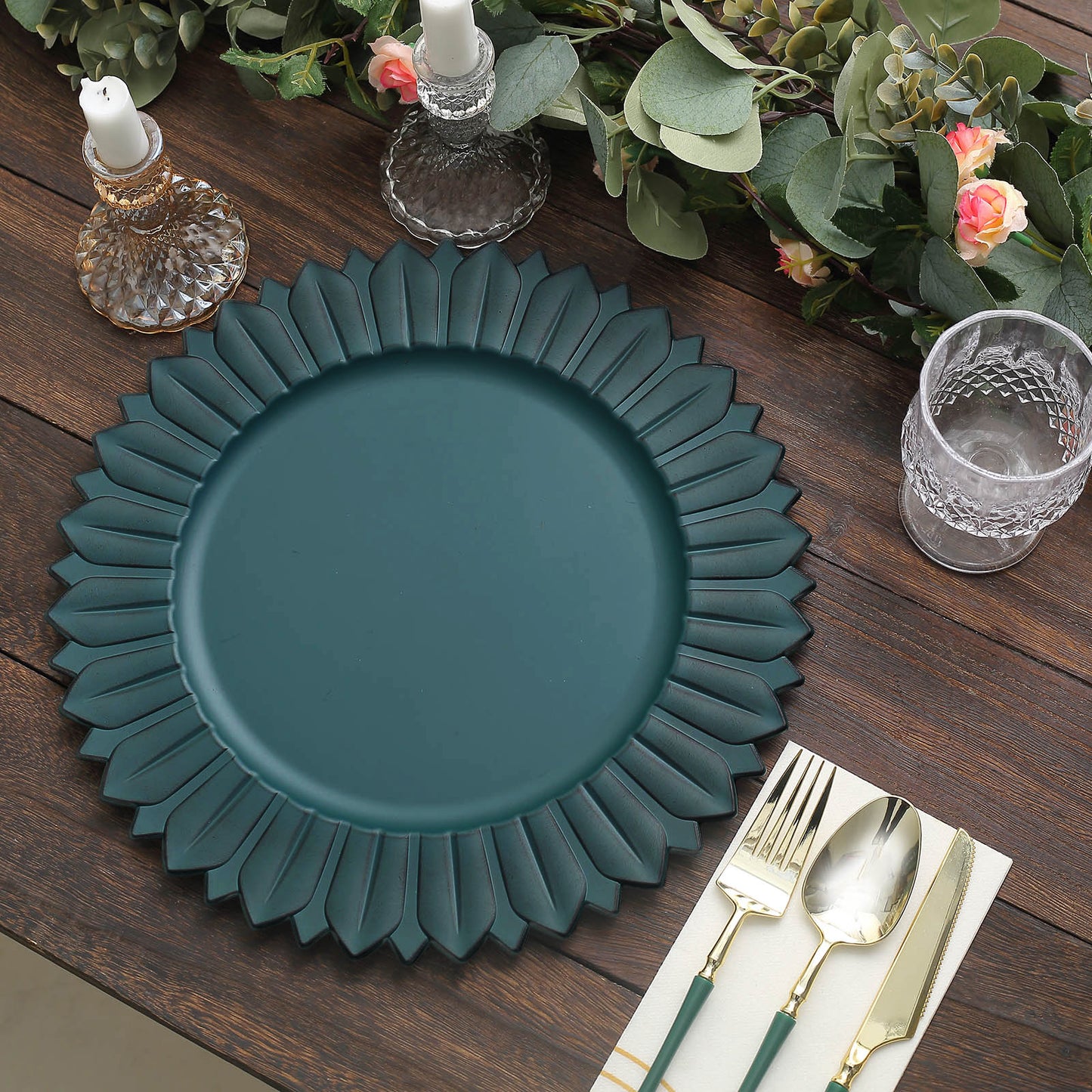 Matte teal sunflower disposable charger plate on a wooden table setting.