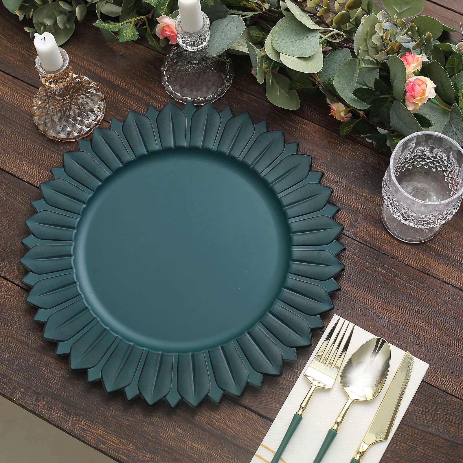 Matte teal sunflower disposable charger plate on a wooden table setting.