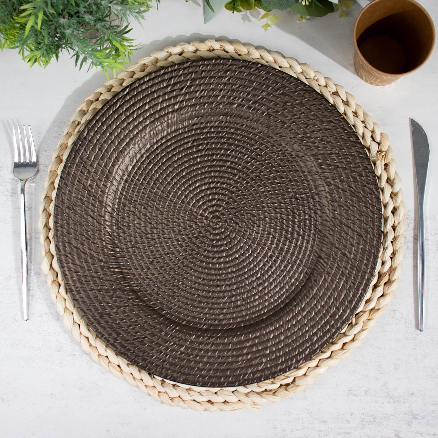 Natural brown acrylic round charger plate with rattan-like design on a table setting.
