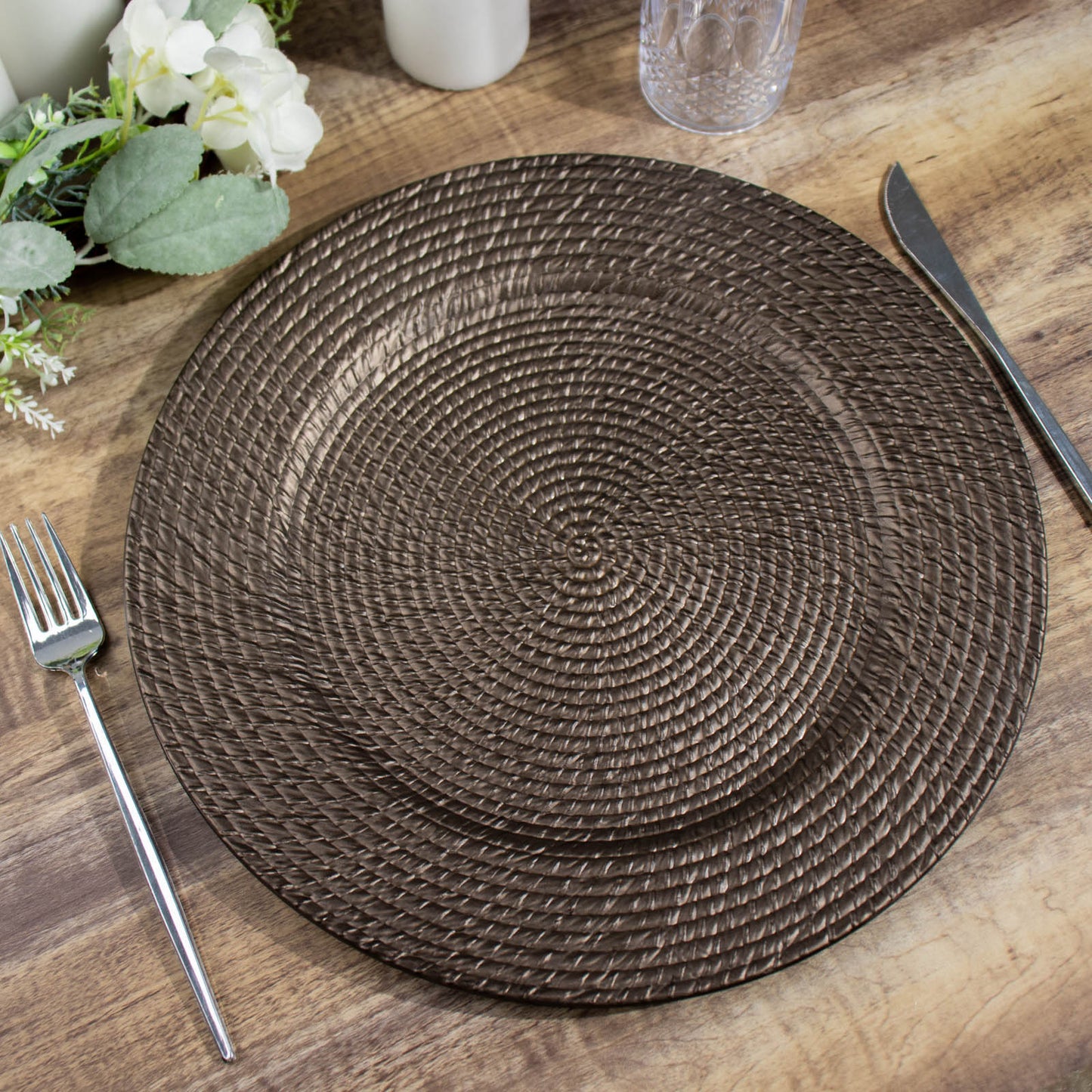 Natural brown acrylic charger plate with rattan-like design on a wooden table.