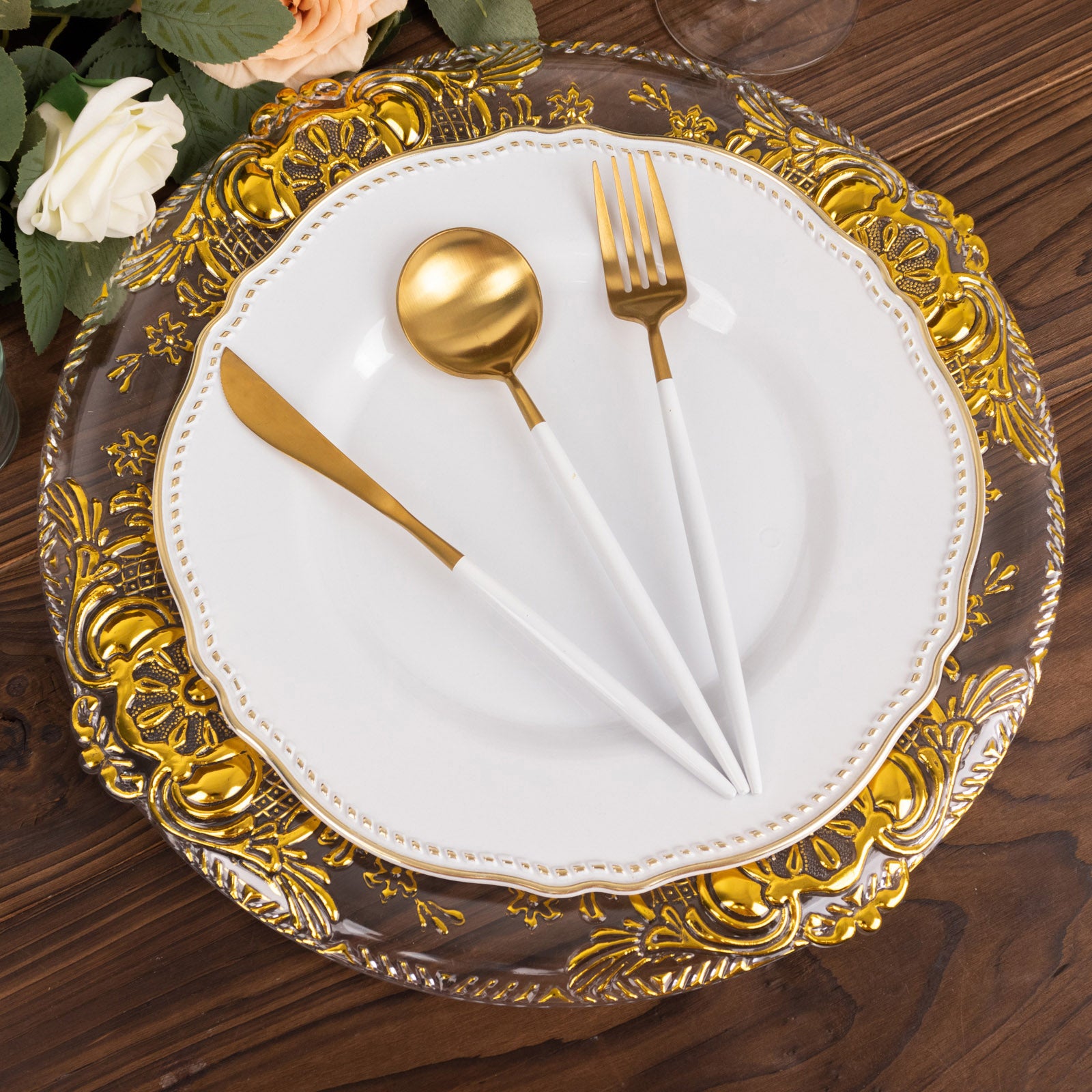 Clear decorative charger plates with gold embossed rim on a wooden table.