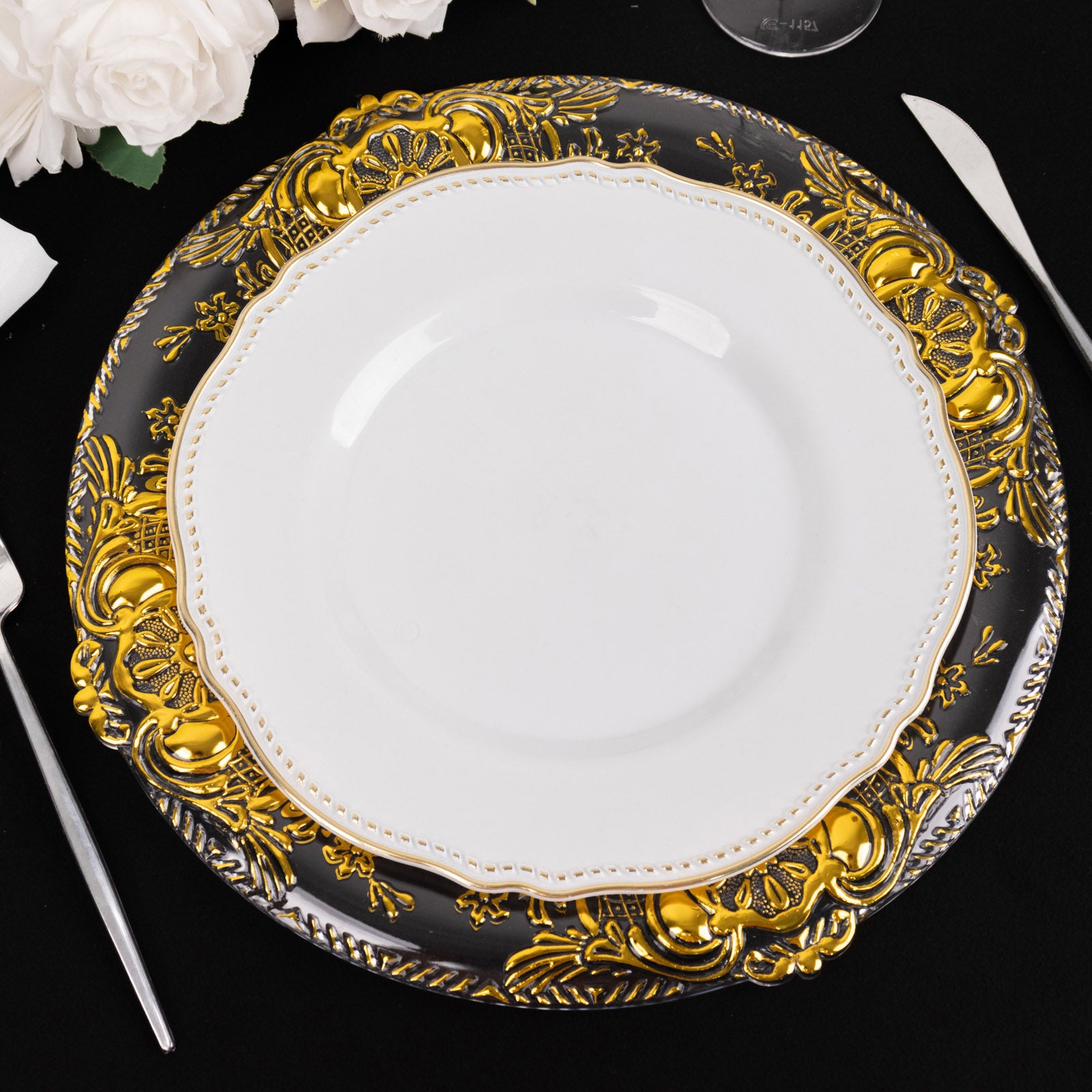 Clear decorative charger plate with gold embossed rim on a black background.