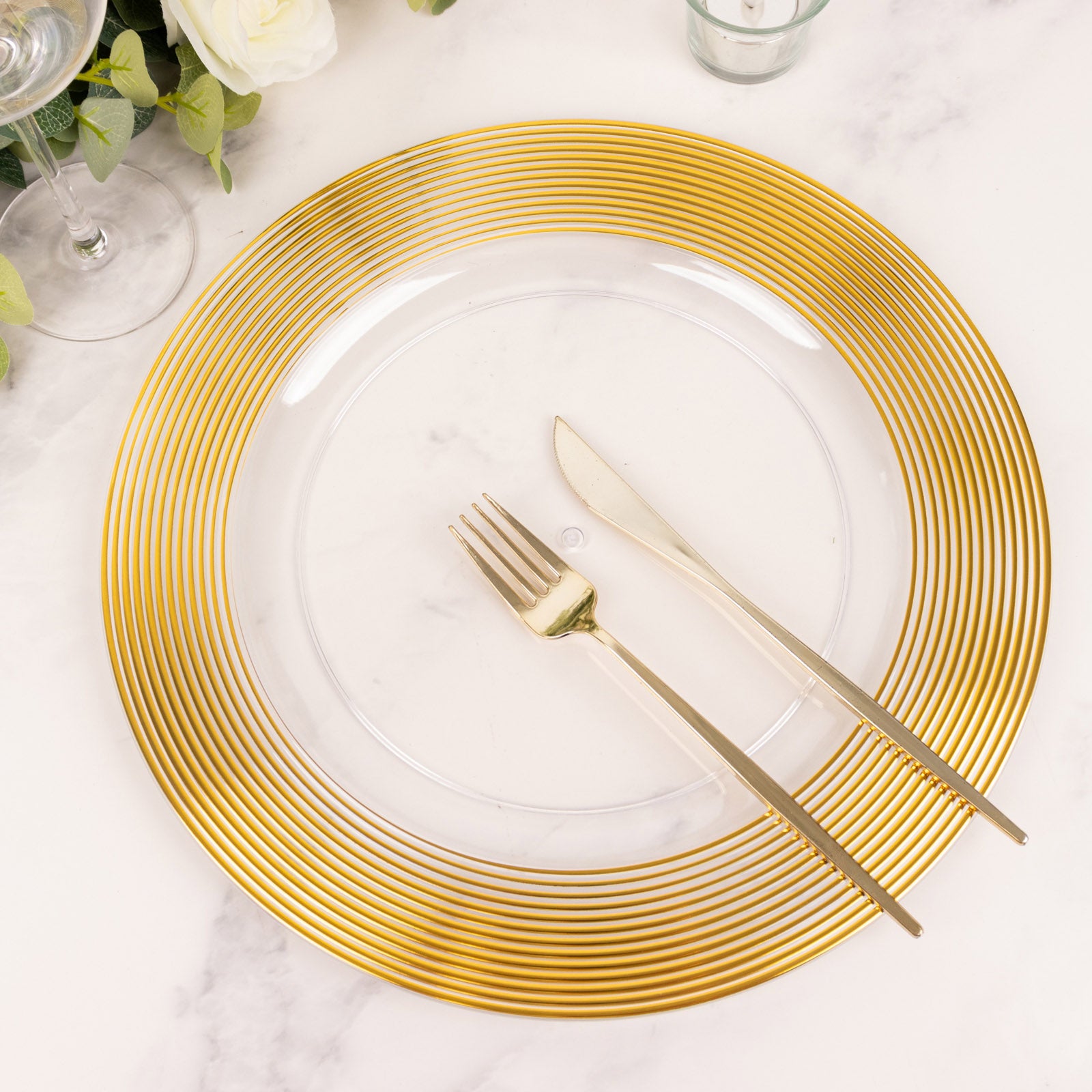 Clear and gold lined rim disposable charger plate on a marble surface.
