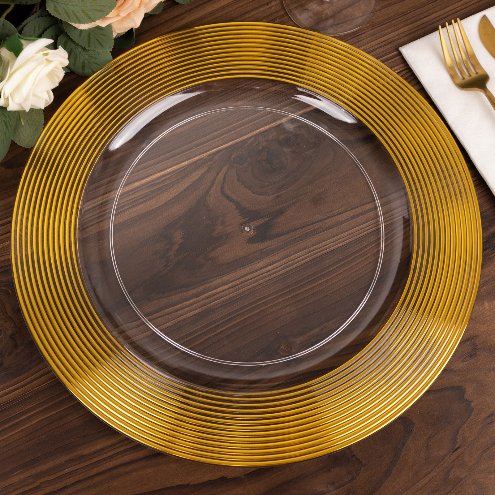 Clear and gold lined rim disposable wedding charger plate on a wooden table.