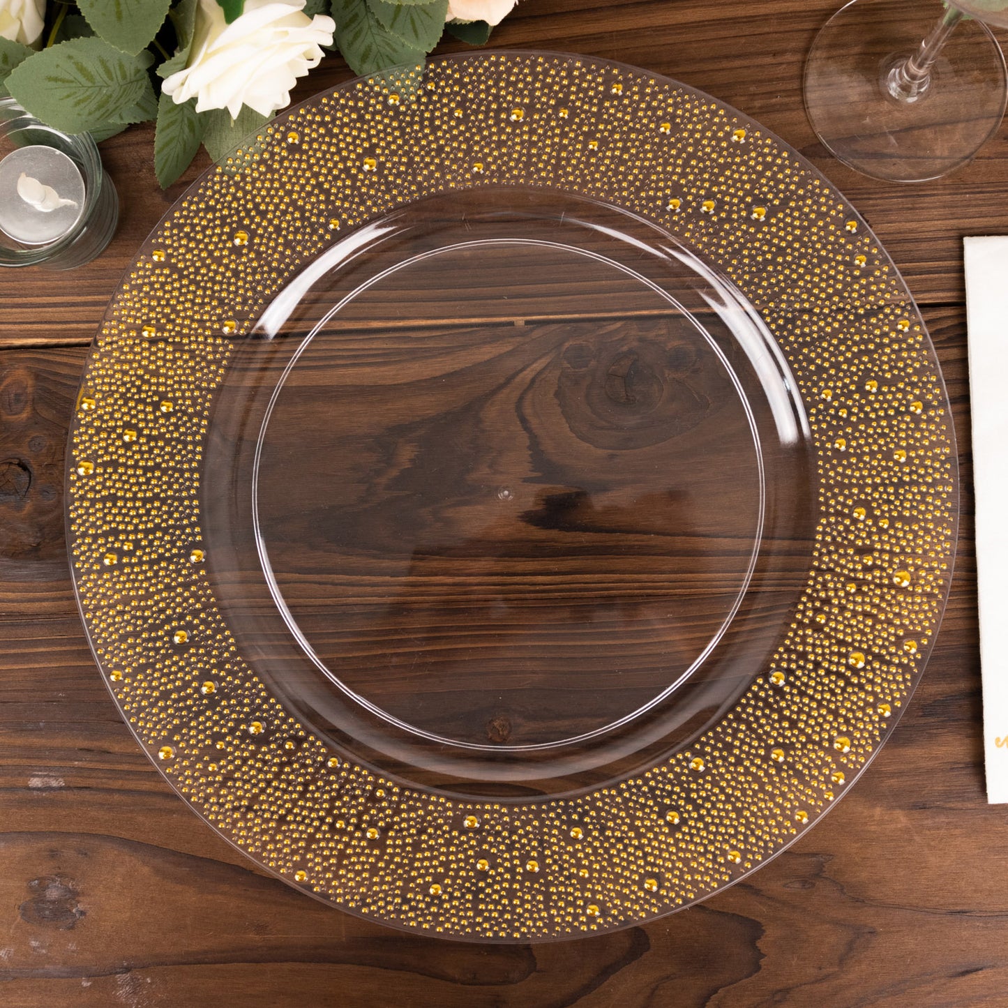 Clear and gold pearl beaded disposable wedding charger plate on a wooden table.