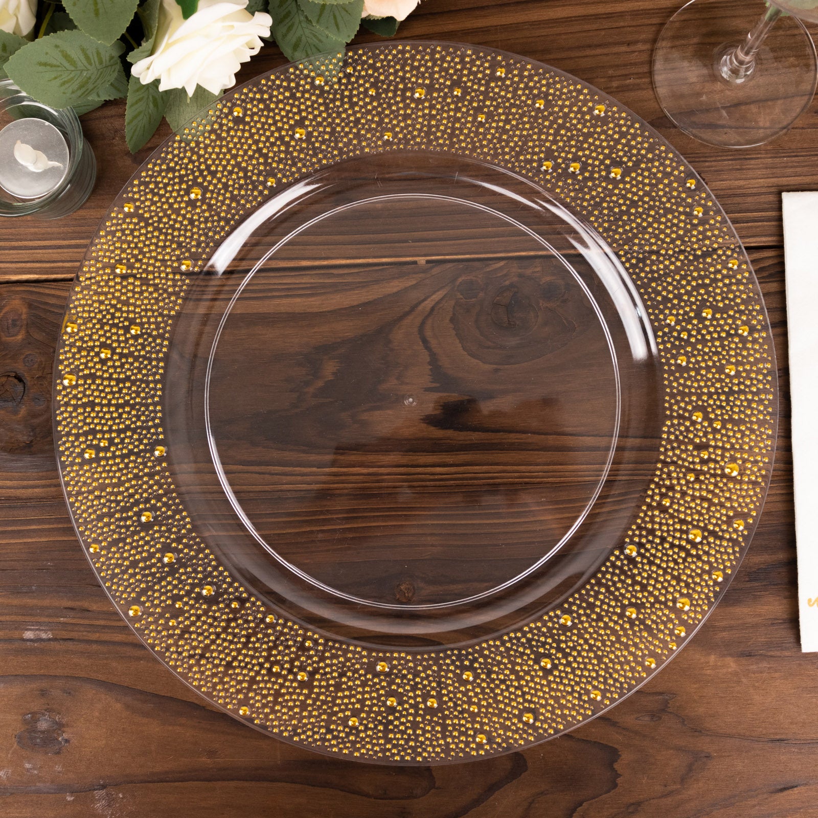 Clear and gold pearl beaded disposable wedding charger plate on a wooden table.