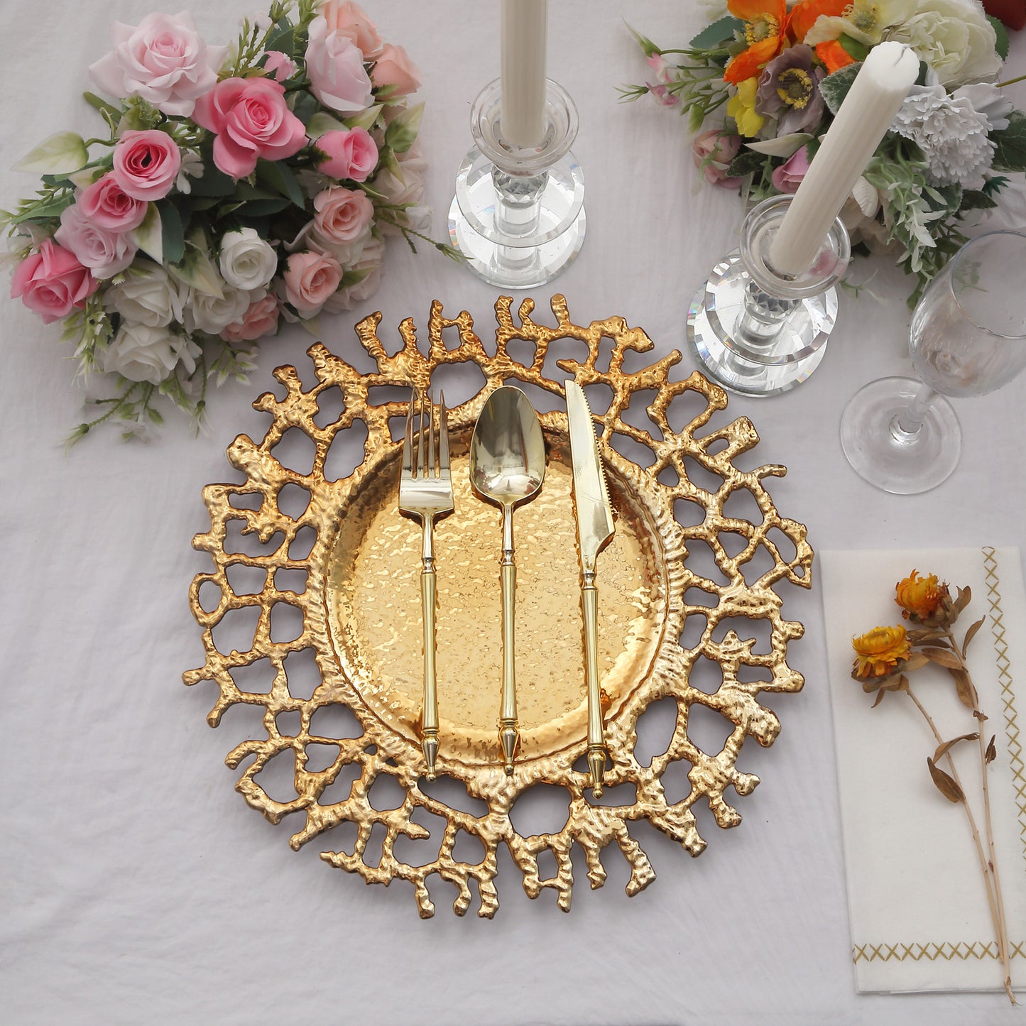 Gold molten branch acrylic charger plates on a dining table setting.