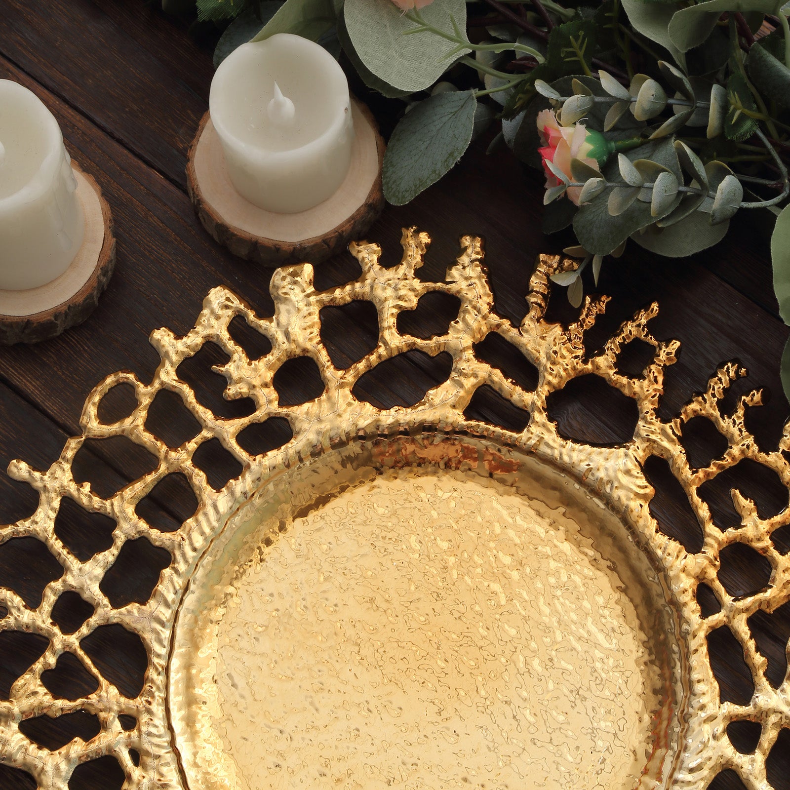 Gold molten branch acrylic charger plate on a rustic wooden surface with candles and greenery.