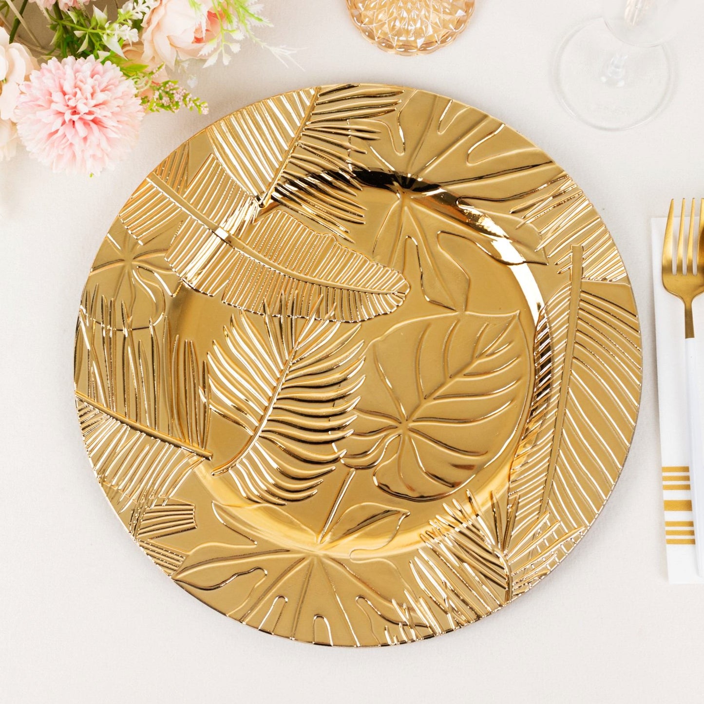 Metallic gold charger plate with embossed tropical leaves design.