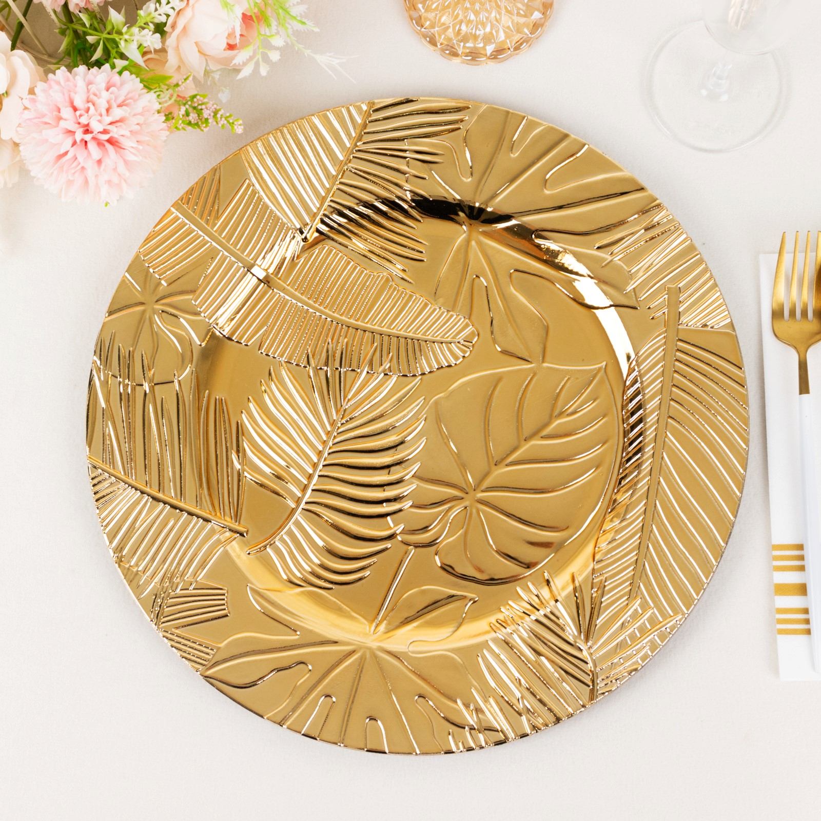Metallic gold charger plate with embossed tropical leaves design.