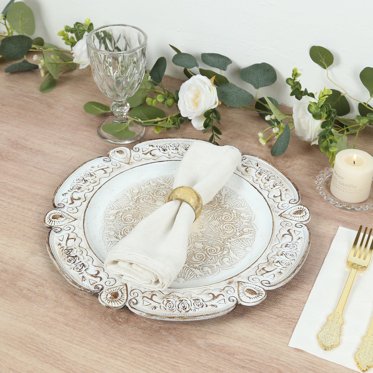 Antique white round acrylic charger plate with floral embossed rim on a table setting.