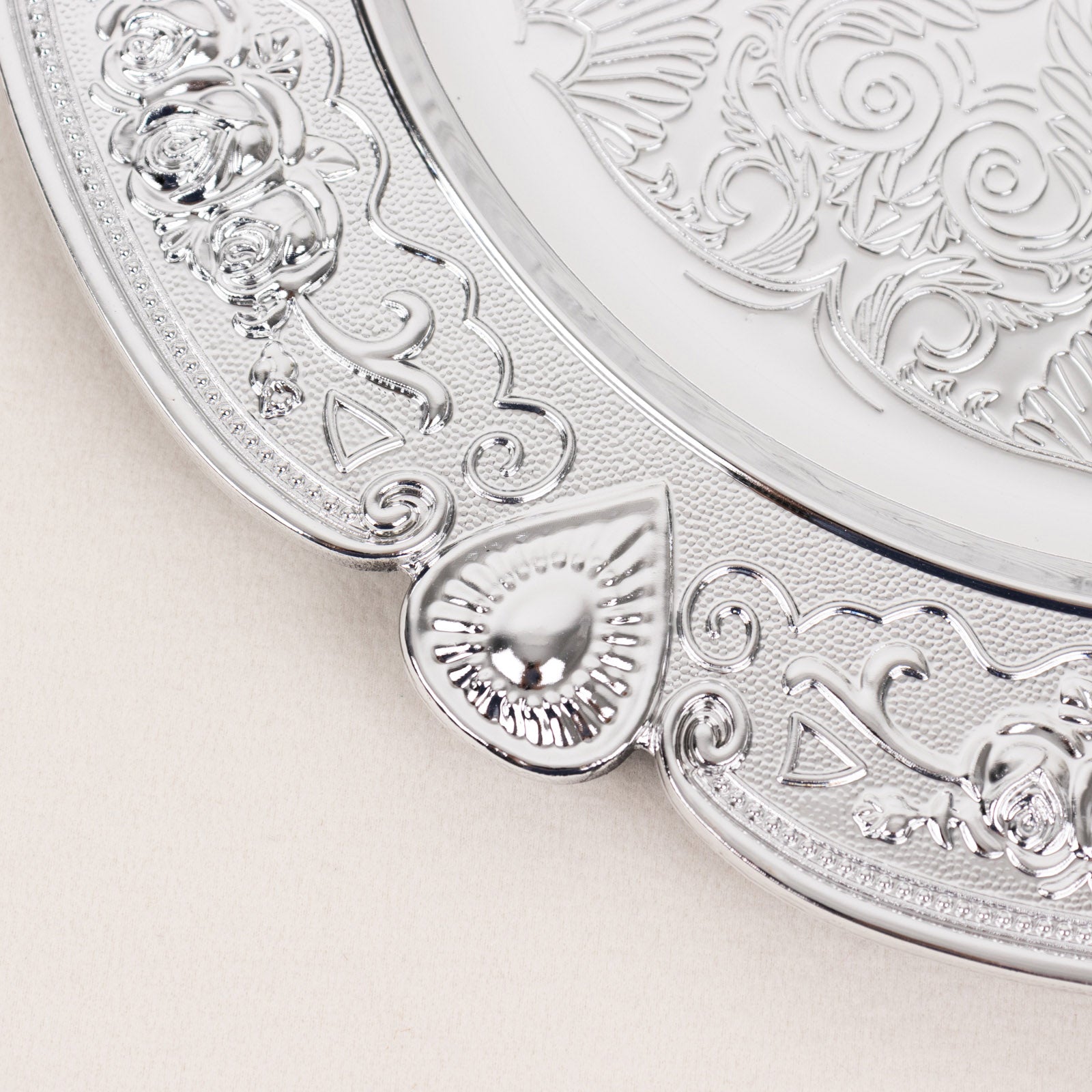 Silver round acrylic charger plate with floral embossed scalloped rim.